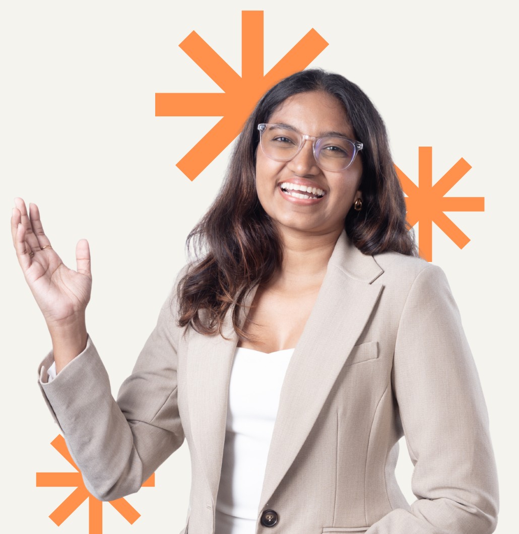 Chamathka smiling and waving, in a beige blazer