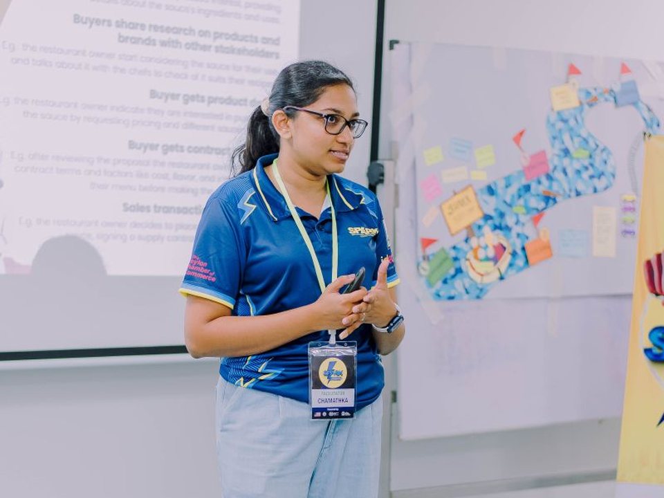 Chamathka facilitating in front of a slide and a sticky-note board
